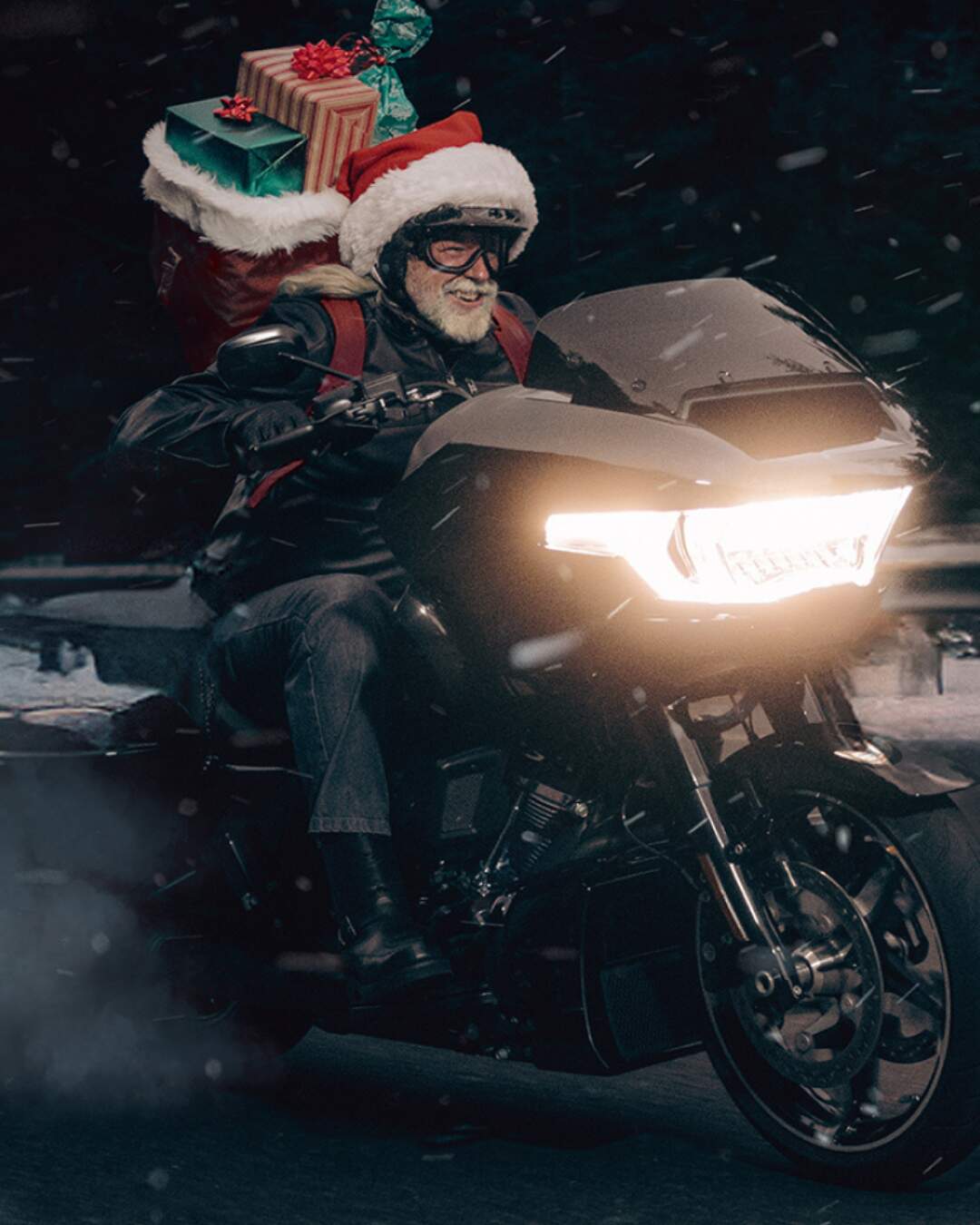 Ein Motorradfahrer im Nikolaus-Look auf einer schwarzen Harley-Davidson Road Glide mit Geschenken im Gepäck