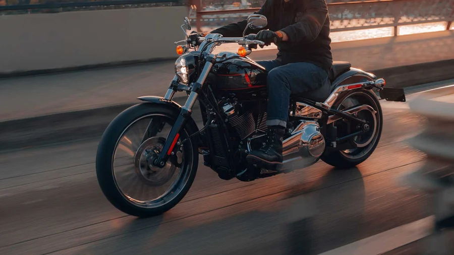 Eine Person fährt auf einem Harley-Davidson Motorrad entlang einer Straße bei Sonnenuntergang.
