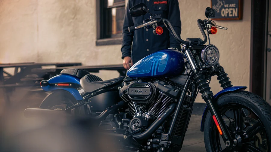 Eine blaue Harley-Davidson-Motorrad mit einem Fahrer im Hintergrund, der an einem offenen Restaurant steht.