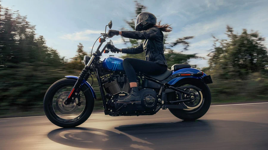 Eine Person fährt dynamisch auf einer blauen Harley-Davidson-Maschine entlang einer Straße.